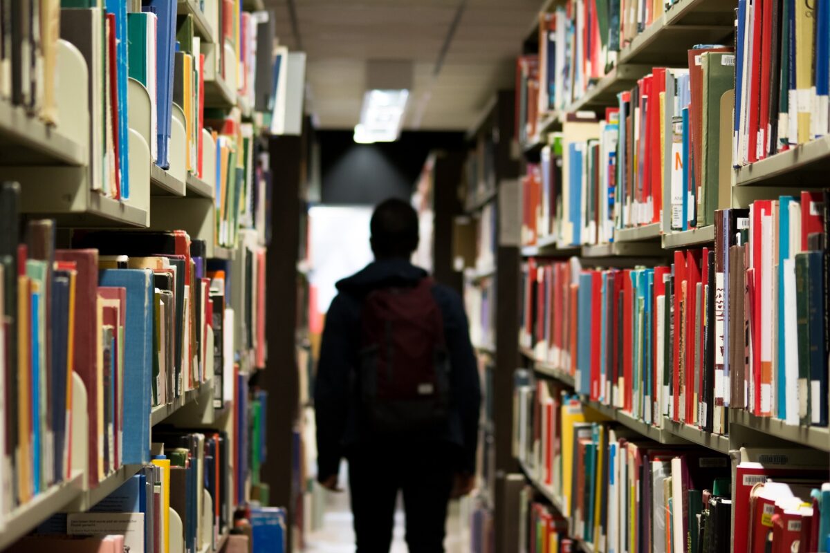 student standing between shelves in a library